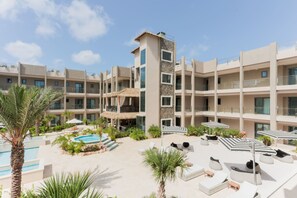A resort with multiple buildings, a swimming pool, and outdoor seating areas. - Modern Condo Near Eagle Beach-Balcony, Pool & Gym, Brand new Walishali Condo (Oranjestad)