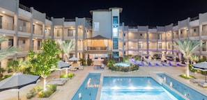 A hotel with multiple swimming pools, outdoor seating areas, and a central bar/lounge area. - Modern Condo Near Eagle Beach-Balcony, Pool & Gym, Brand new Walishali Condo (Oranjestad)