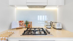 A modern kitchen with a gas stove, a coffee maker, and a toaster. - Zen Botanica Waterfront Sea View Pool Quiet (Darwin)