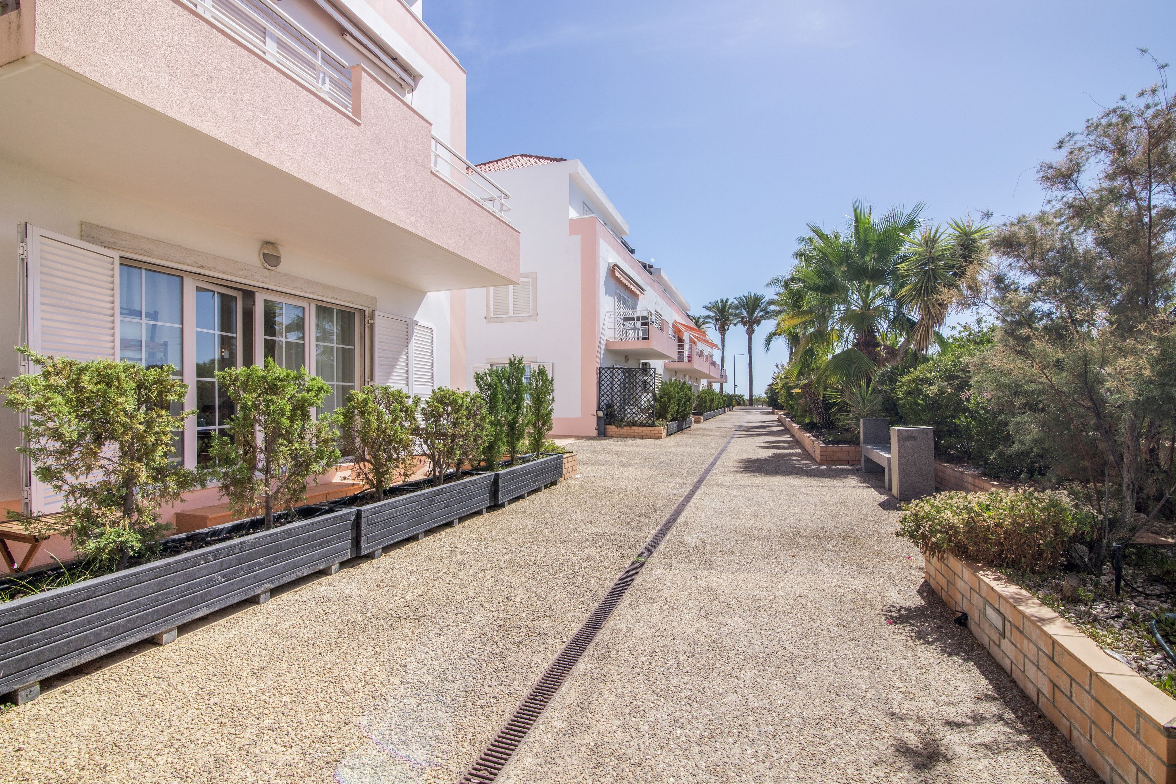 A pathway leading to a building with multiple balconies and a gravel surface.