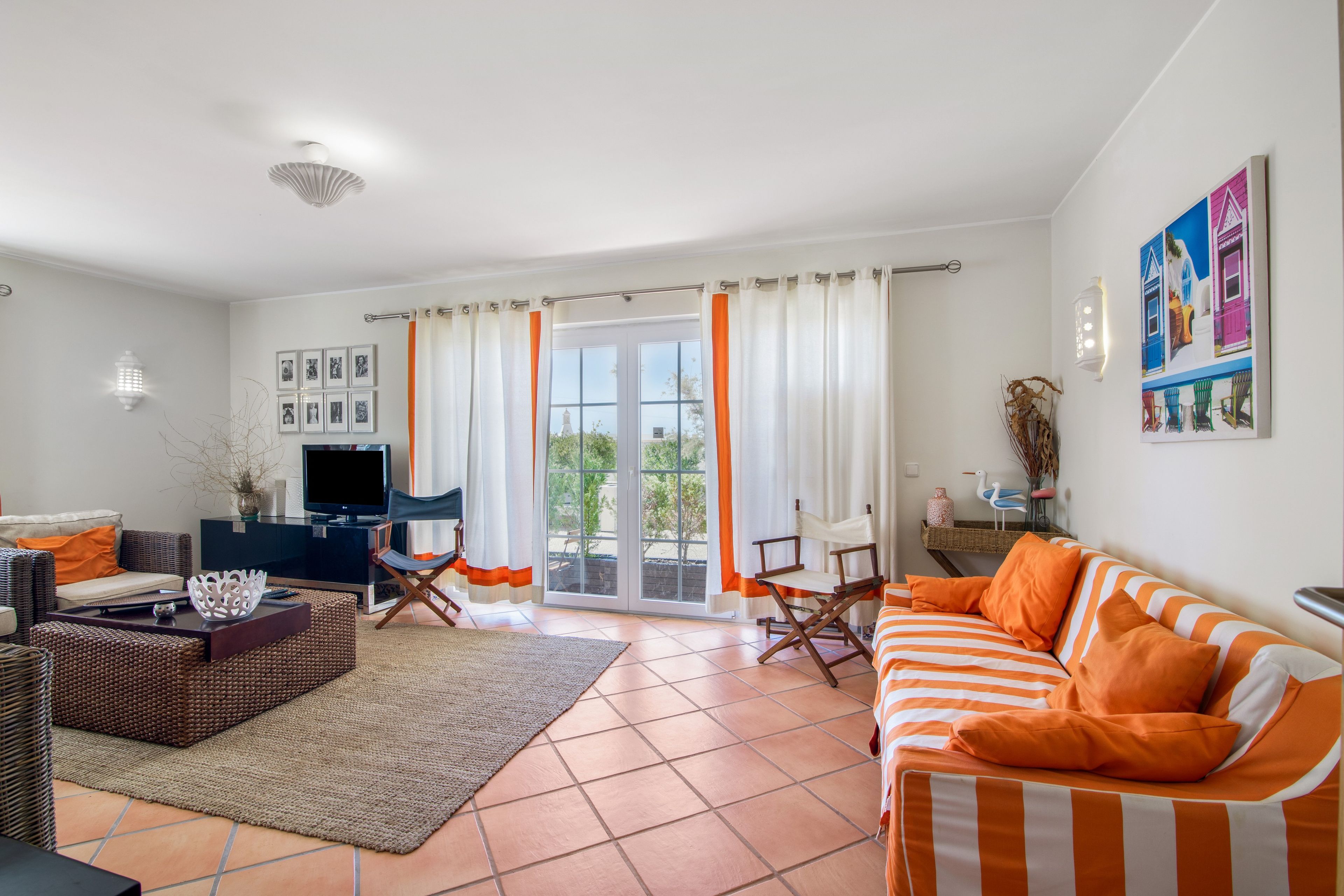 A living room with a sofa, television, and a view through a glass door.