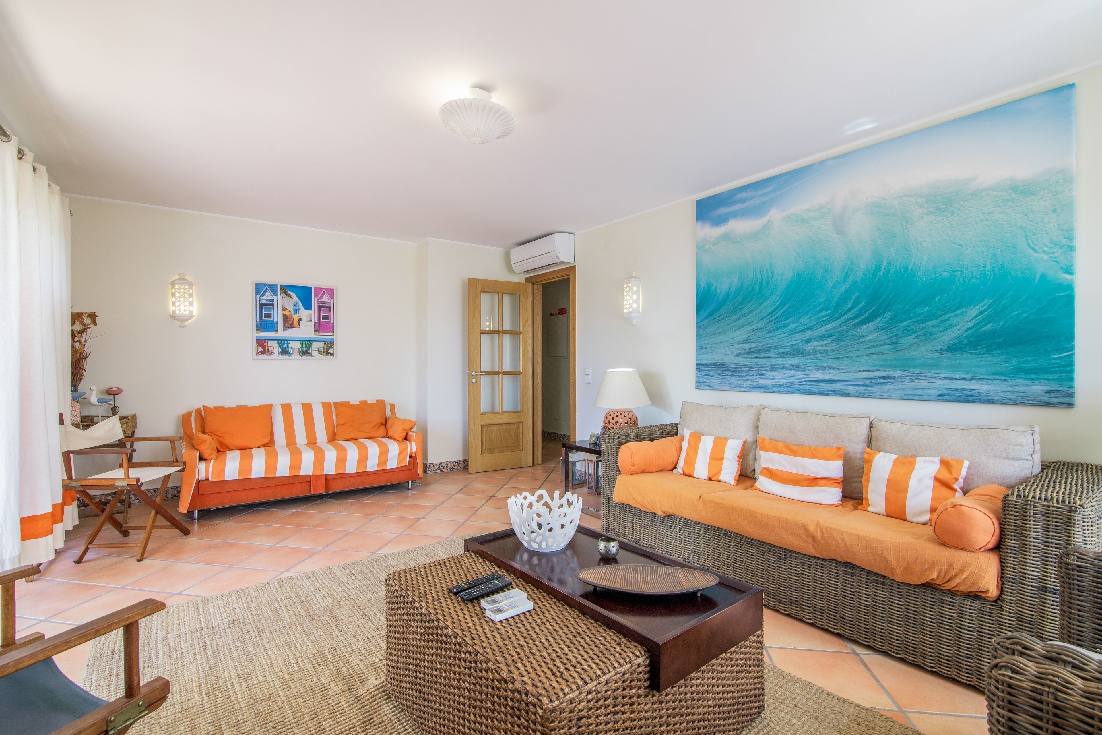 A living room with two sofas, a coffee table, and a large wave painting on the wall.
