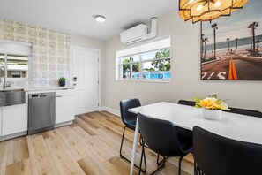 A modern kitchen with white cabinetry, a dishwasher, and a window with a view of the beach. - Beachside Bungalow - Unit A | 2BR, 8-Min Walk to Beach, Patio & BBQ Grills 🌴 (Cape Canaveral)