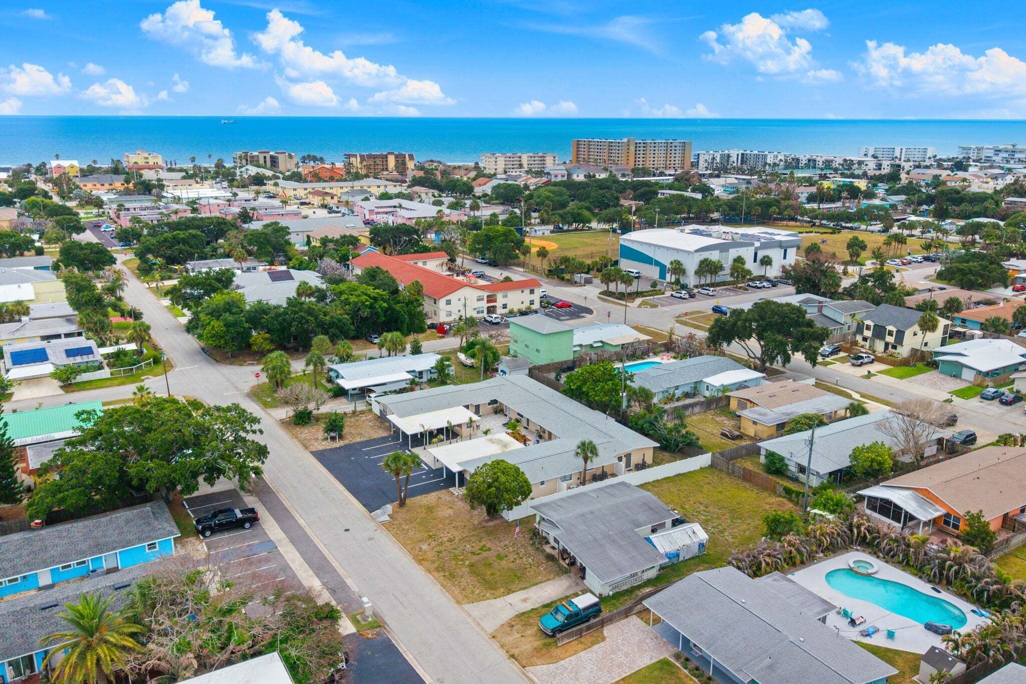 A residential area with houses, a swimming pool, and a view of the ocean.