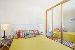 Une chambre d’hôtel avec un lit, deux tables de chevet, un miroir et un tableau accroché au mur.