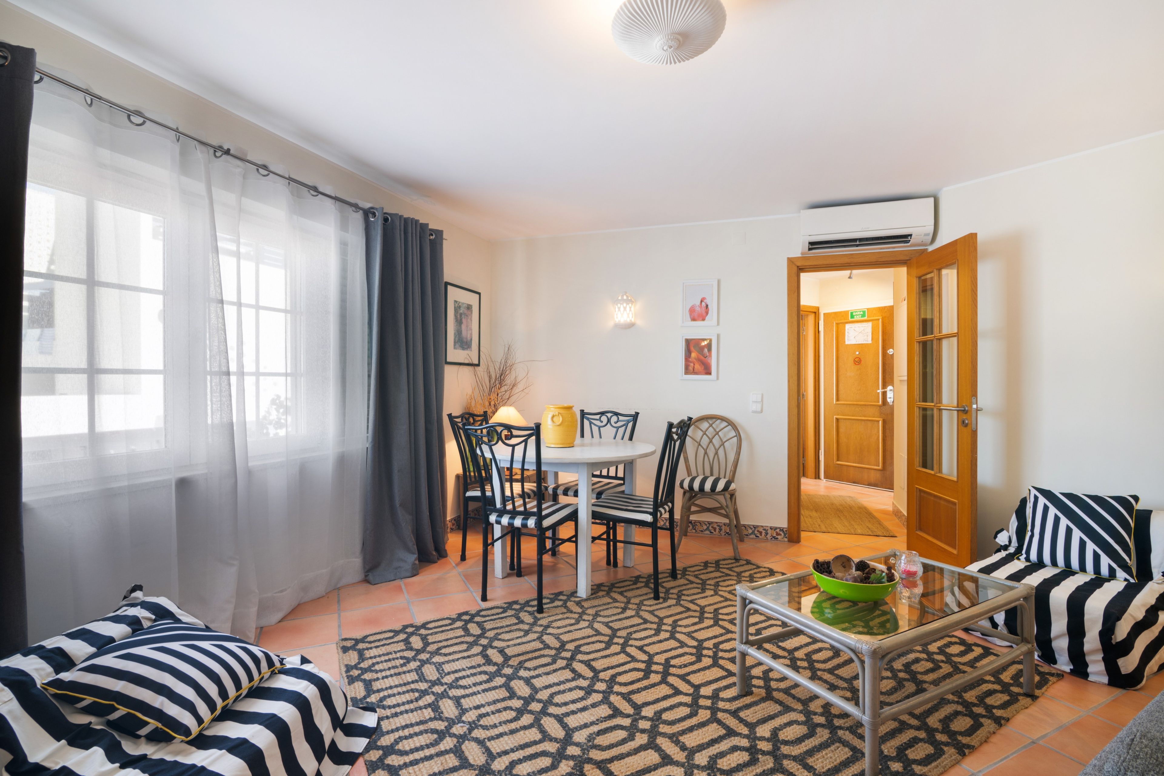Un salon comprenant un coin repas, un ensemble de canapés, une table basse et une vue sur l’extérieur.