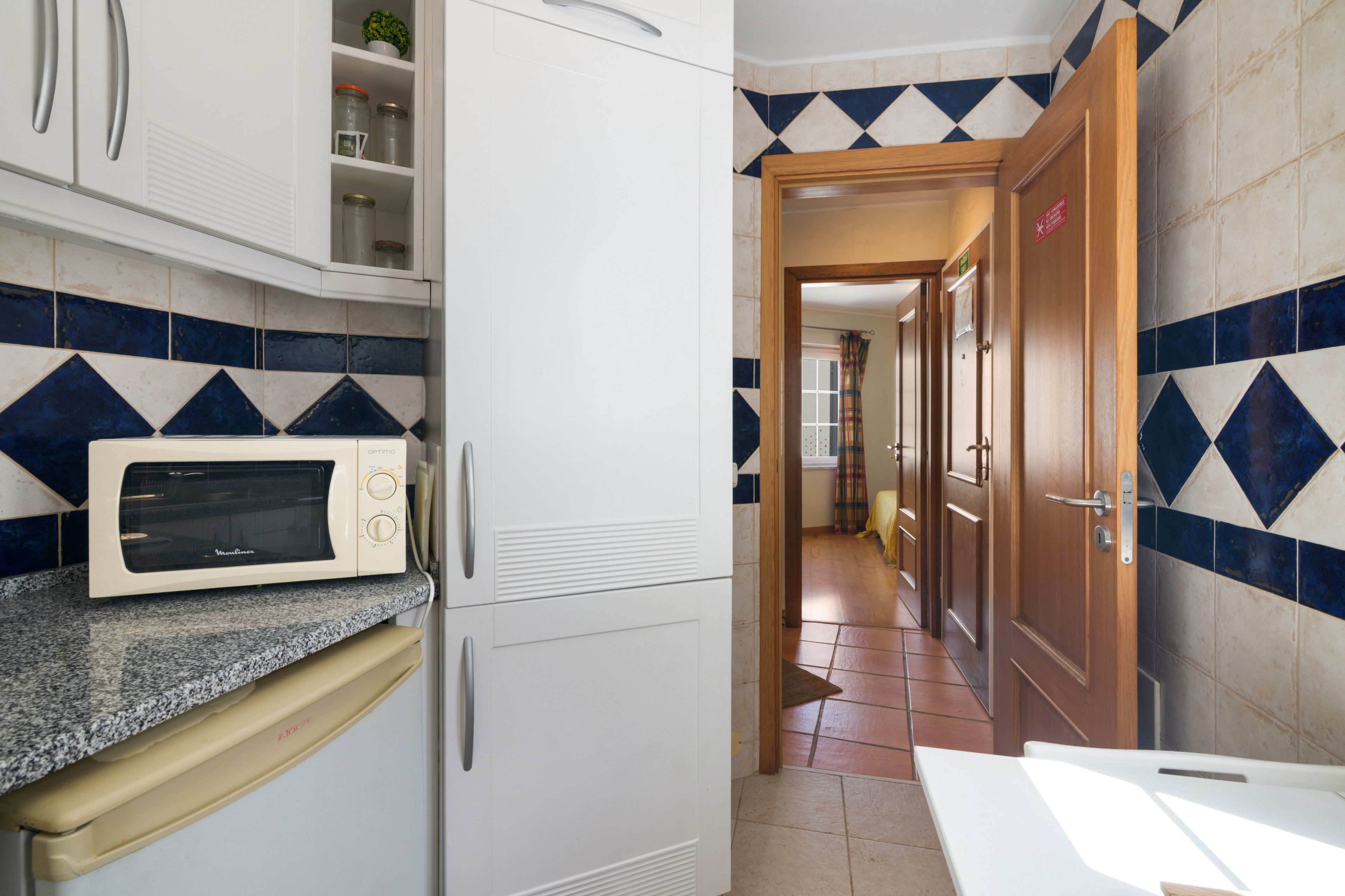 A kitchen with a microwave, cabinets, and a tiled backsplash.