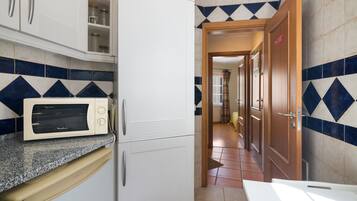 A kitchen with a microwave, cabinets, and a tiled backsplash.