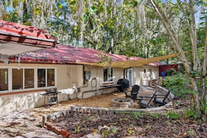 A house with a red roof, a covered patio area, and a fire pit.