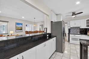 A modern kitchen with white cabinetry, a black granite countertop, and stainless steel appliances.