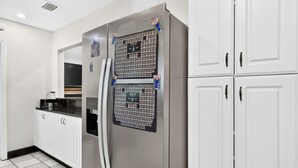 Eine Küche mit einem Edelstahl-Kühlschrank, weißen Schränken und einem Fliesenboden.