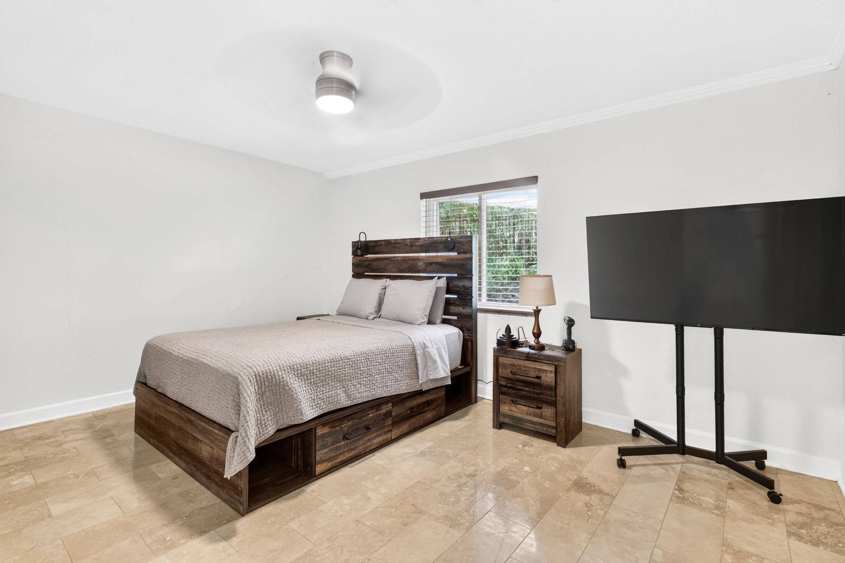 Ein Schlafzimmer mit Bett, Nachttisch, Lampe und einem Fernsehmöbel.