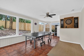 A room with a ping pong table, a ceiling fan, and dartboards on the wall. - Chompers Den - Walk to the Swamp! (Gainesville)