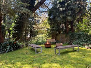 A garden with two benches, a fire pit, and lush greenery. - Kallista Silvermist House by Ready Set Stay (Kallista)