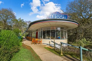 A tea room with a curved roof, large windows, and outdoor seating. - Kallista Silvermist House by Ready Set Stay (Kallista)