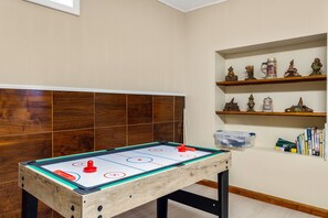 A room with a foosball table, wooden shelving with decorative items, and a window. - The Adventure House | Sauna | Kayak (Superior)