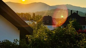 A sunset over a residential area with houses and hills in the background.