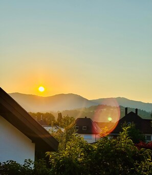 A sunset over a residential area with houses and hills in the background.