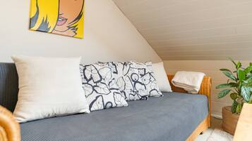 Ein Schlafzimmer mit einem Bett, Kissen, einem Gemälde und einer Pflanze.