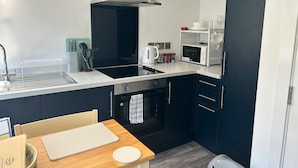 A compact kitchen with a stove, oven, microwave, and a modern sink.