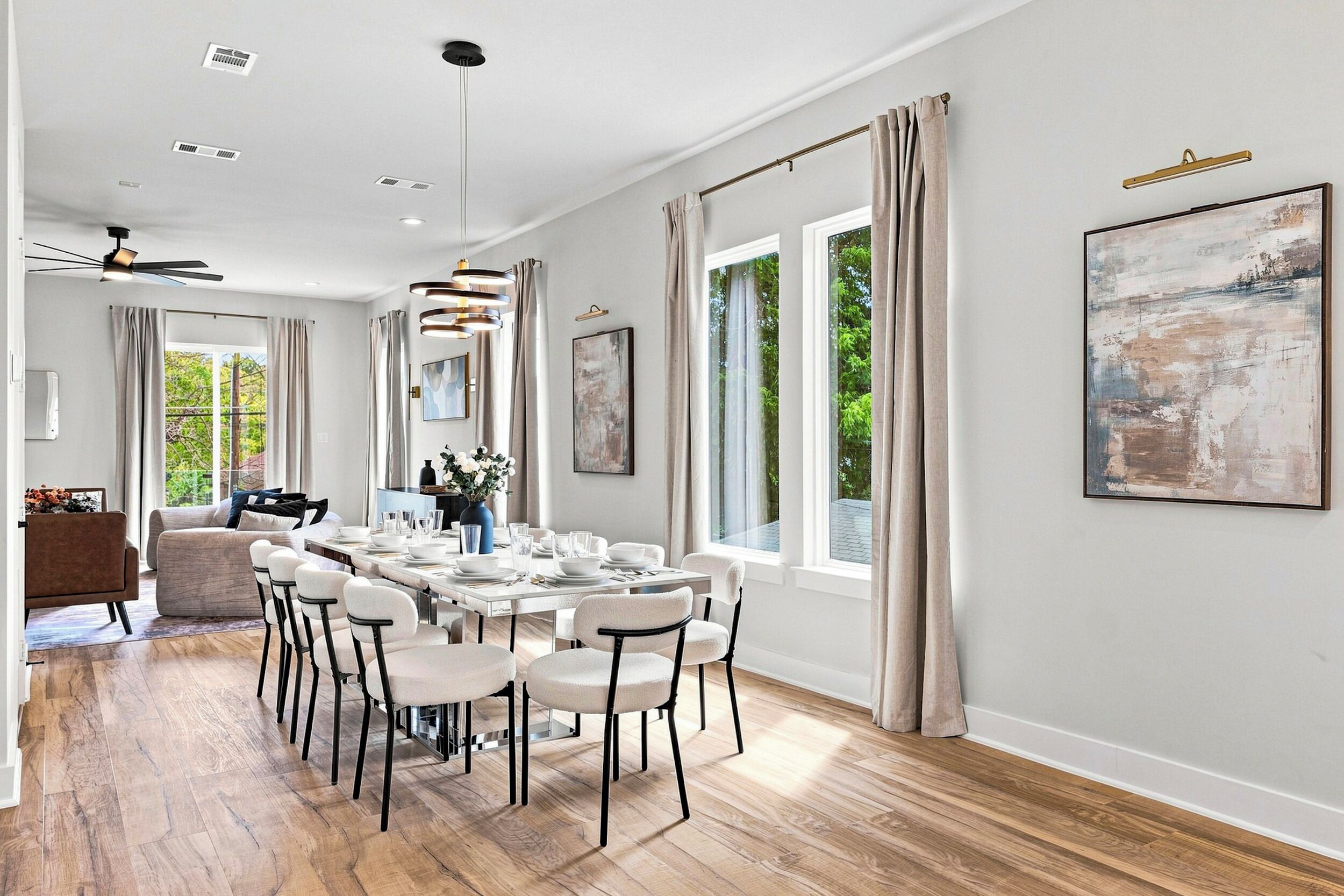 Uma sala de jantar moderna com uma mesa comprida posta para seis pessoas, rodeada por cadeiras brancas com estrutura preta.