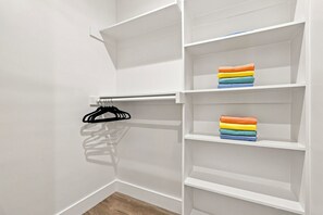 Ein Schrank mit weißen Regalen und einer Kleiderstange.