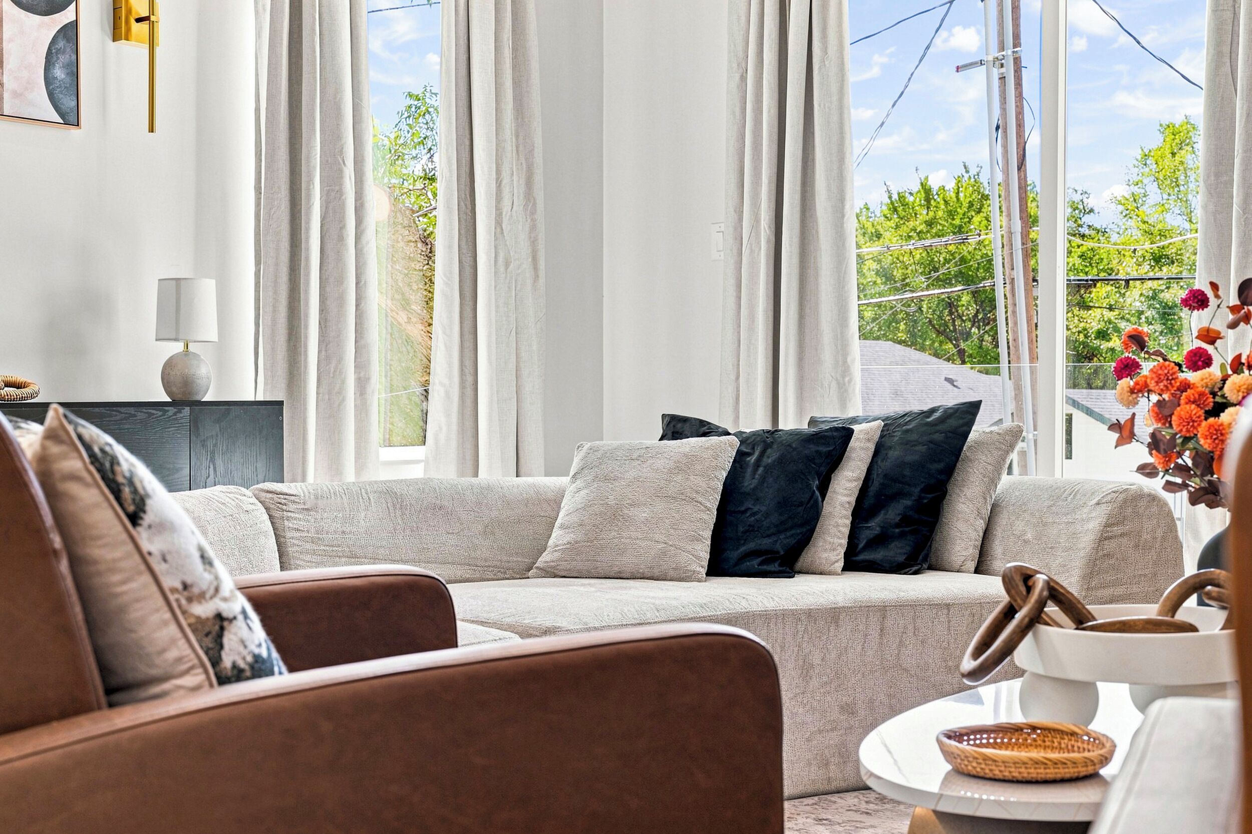 Un salon moderne avec un canapé beige, une table basse et un vase rempli de fleurs.