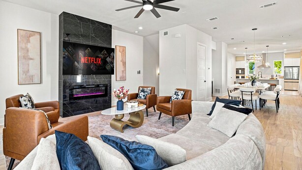 A modern living room with a fireplace, comfortable seating, and a ceiling fan. - Modern Dallas Retreat | Rooftop, Hot Tub & Views (Dallas)