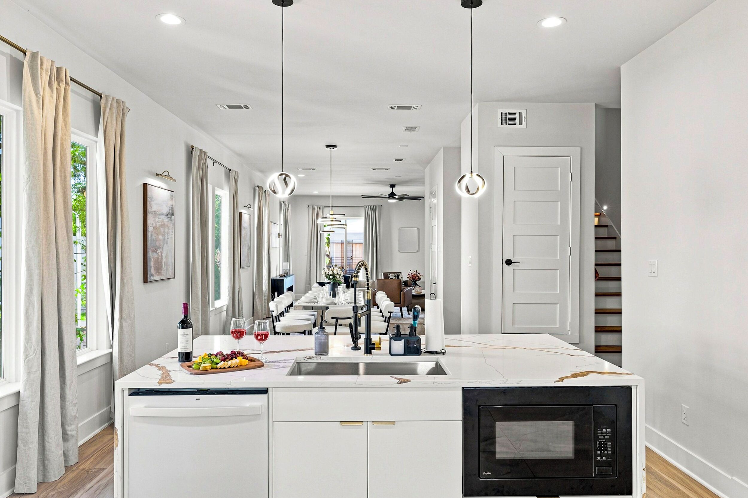 Una cocina moderna con una isla central, armarios blancos y un microondas negro.