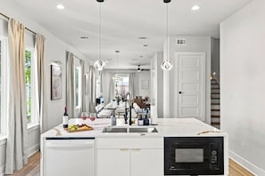Una cocina moderna con una isla central, armarios blancos y un microondas negro.