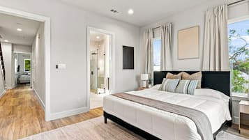 Une chambre moderne avec un grand lit, un dressing et une vue sur l’extérieur.