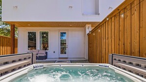A hot tub with a wooden deck and a covered patio area. - Modern Dallas Retreat | Rooftop, Hot Tub & Views (Dallas)