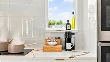 Une cuisine avec une machine à café, un bol et une bouteille posés sur le comptoir.