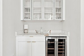 A modern kitchen with white cabinetry, a marble countertop, and a built-in stainless steel refrigerator. - Skyline Rooftop & Hot Tub | Near Trinity Groves (Dallas)
