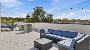 An outdoor seating area with a sofa and chairs, string lights, and air conditioning units. - Luxe Dallas Home w/ Rooftop, Hot Tub, Yard & Views (Dallas)