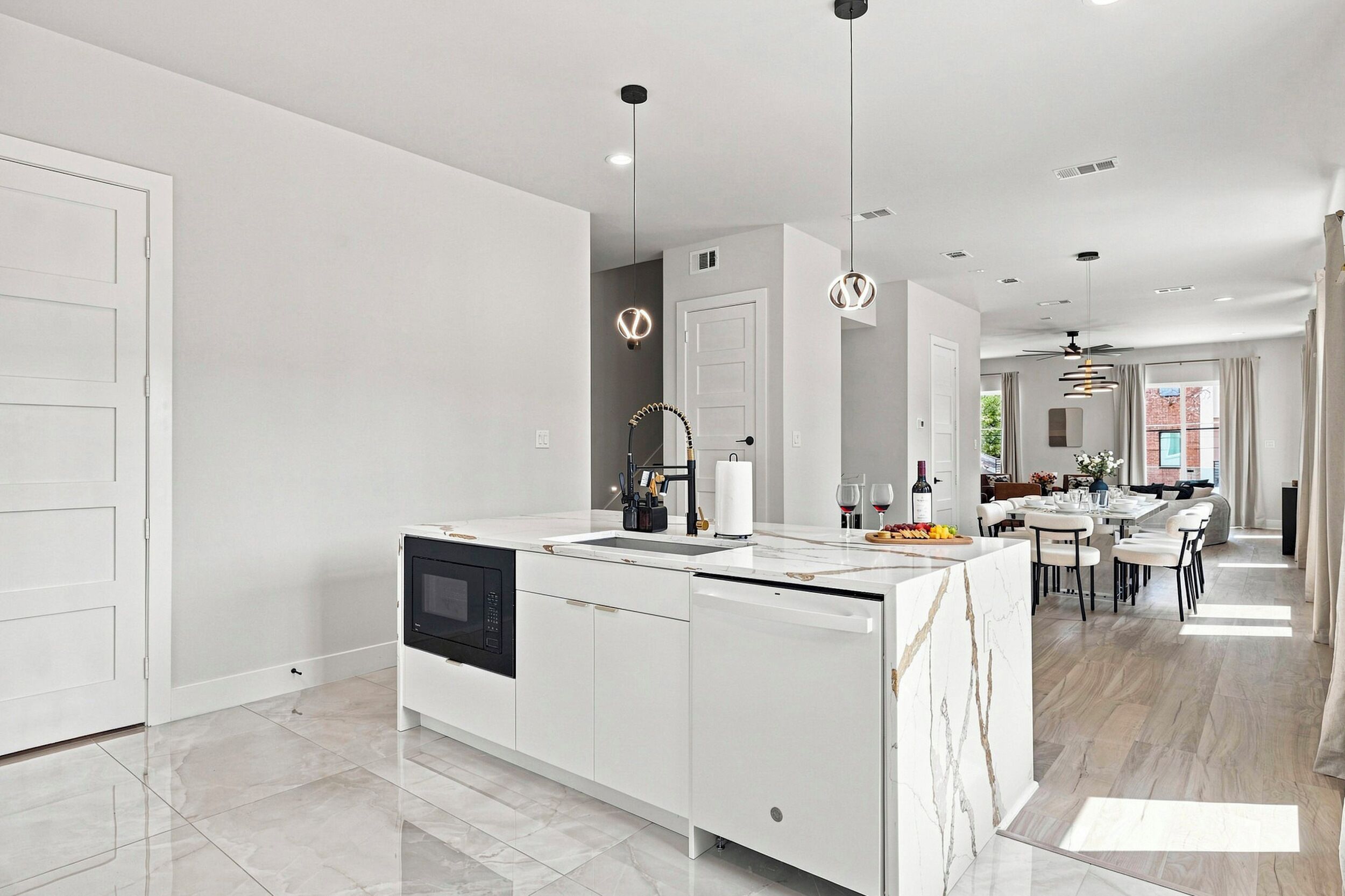 Cocina moderna con una isla central, muebles blancos y un comedor con mesa y sillas.