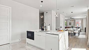 Cocina moderna con una isla central, muebles blancos y un comedor con mesa y sillas.