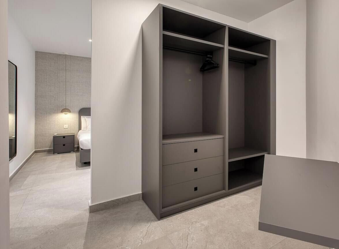 A modern bedroom with a large wardrobe, a bedside table, and a lamp.