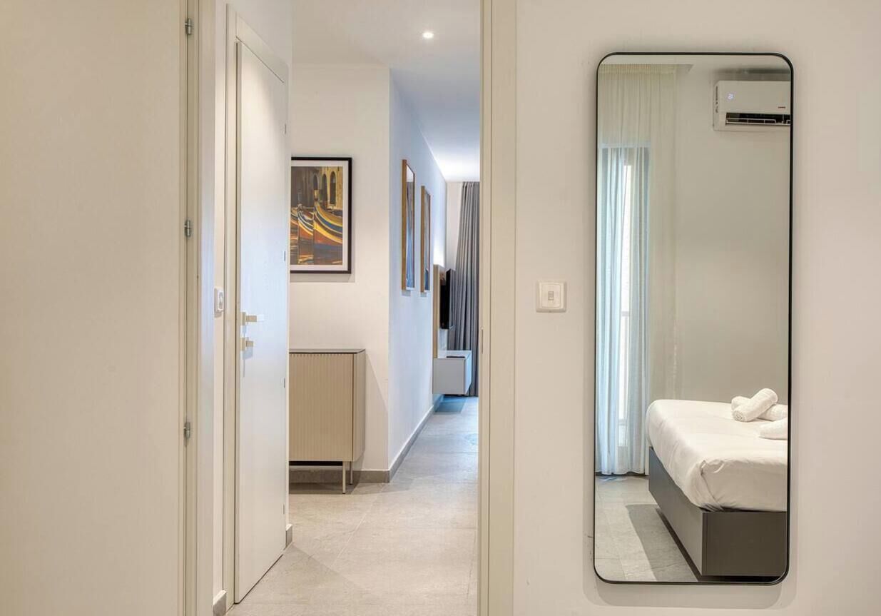 Ein Hotelzimmer mit Bett, Nachttisch, Spiegel und einem Fenster mit Vorhängen.
