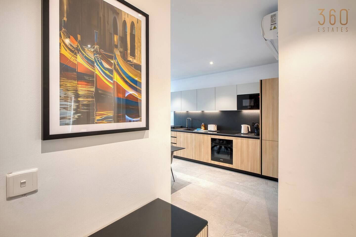 A modern kitchen with wooden cabinets, a black countertop, and a stainless steel microwave.