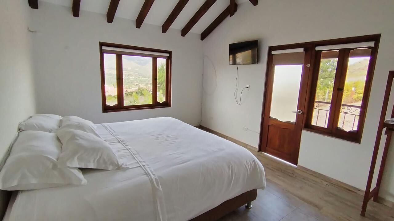 A bedroom with a bed, a TV mounted on the wall, and a balcony door.