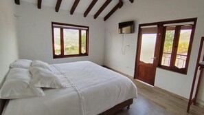 A bedroom with a bed, a TV mounted on the wall, and a balcony door.