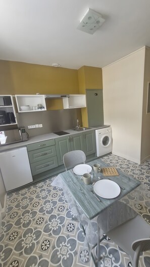 Een kleine keuken met een wasmachine, een magnetron en een koelkast.