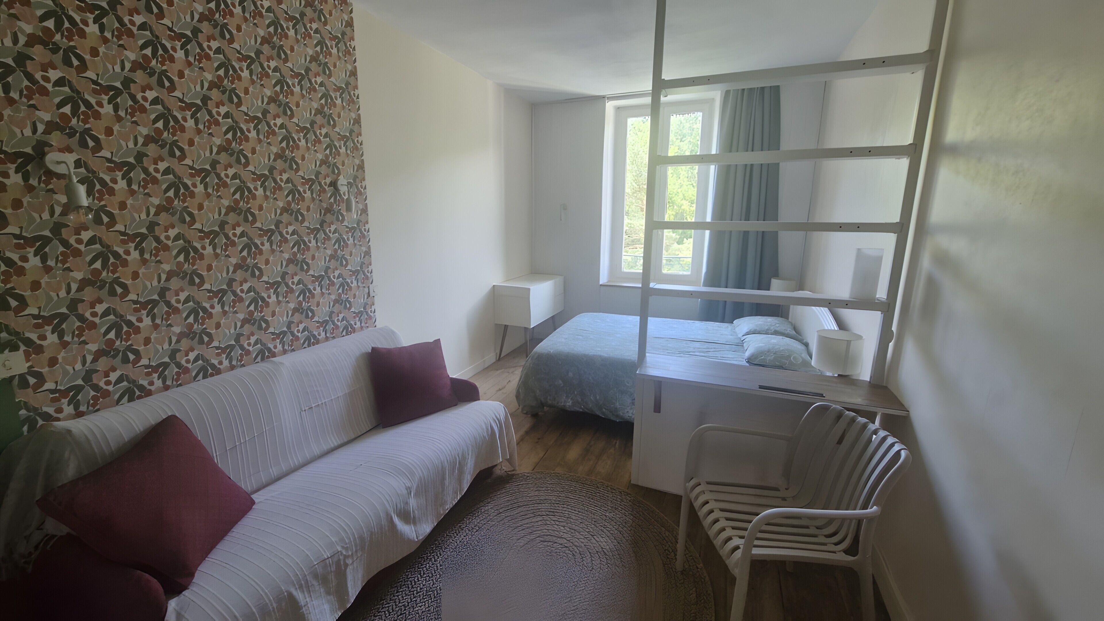 A bedroom with a bunk bed, a single bed, a desk, a chair, and a patterned wall.