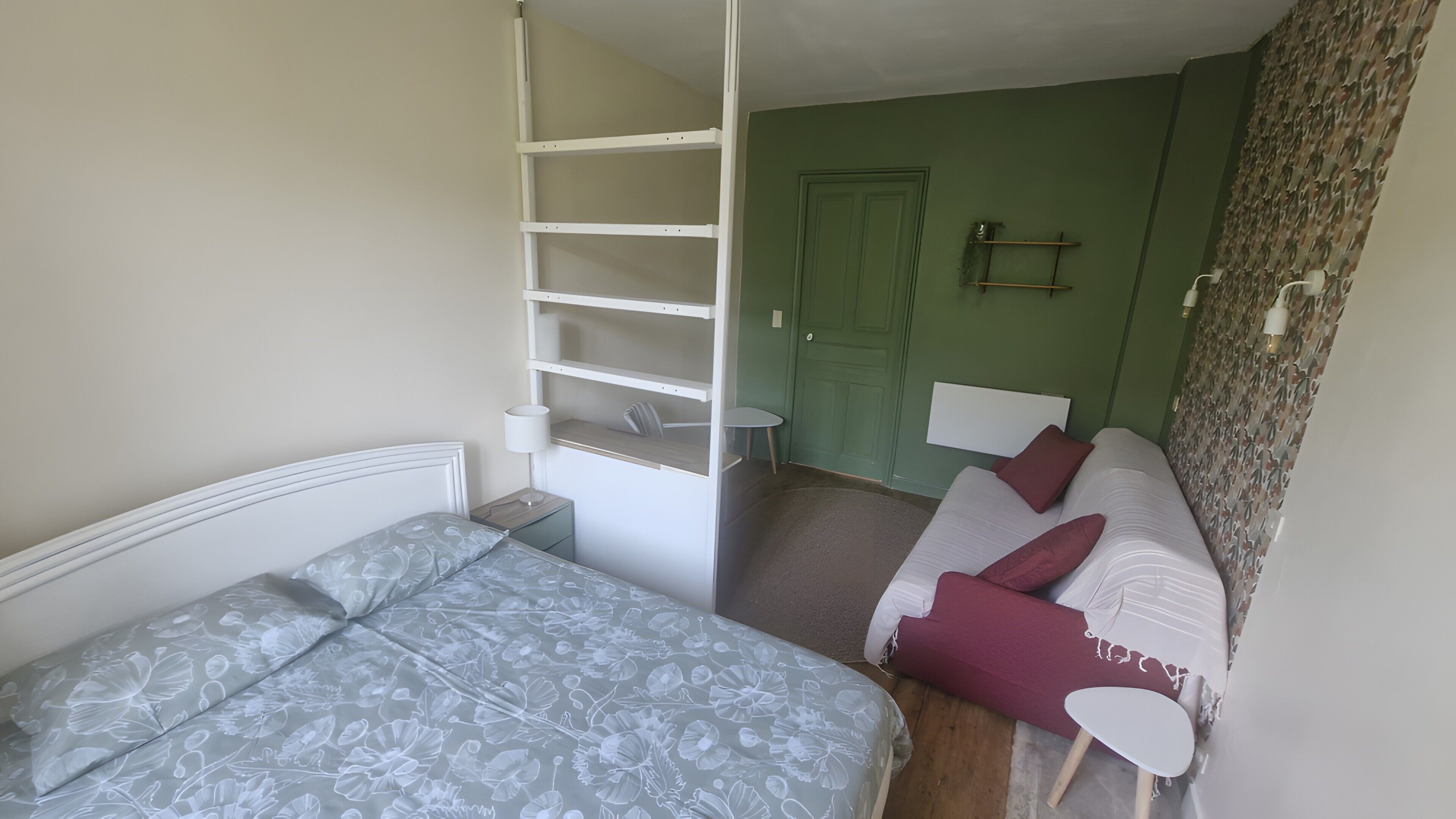 Una habitación con cama, sofá, una mesita y una puerta verde.