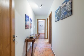 Un couloir avec une porte en bois, une table ornée d’objets décoratifs et des œuvres d’art accrochées aux murs.