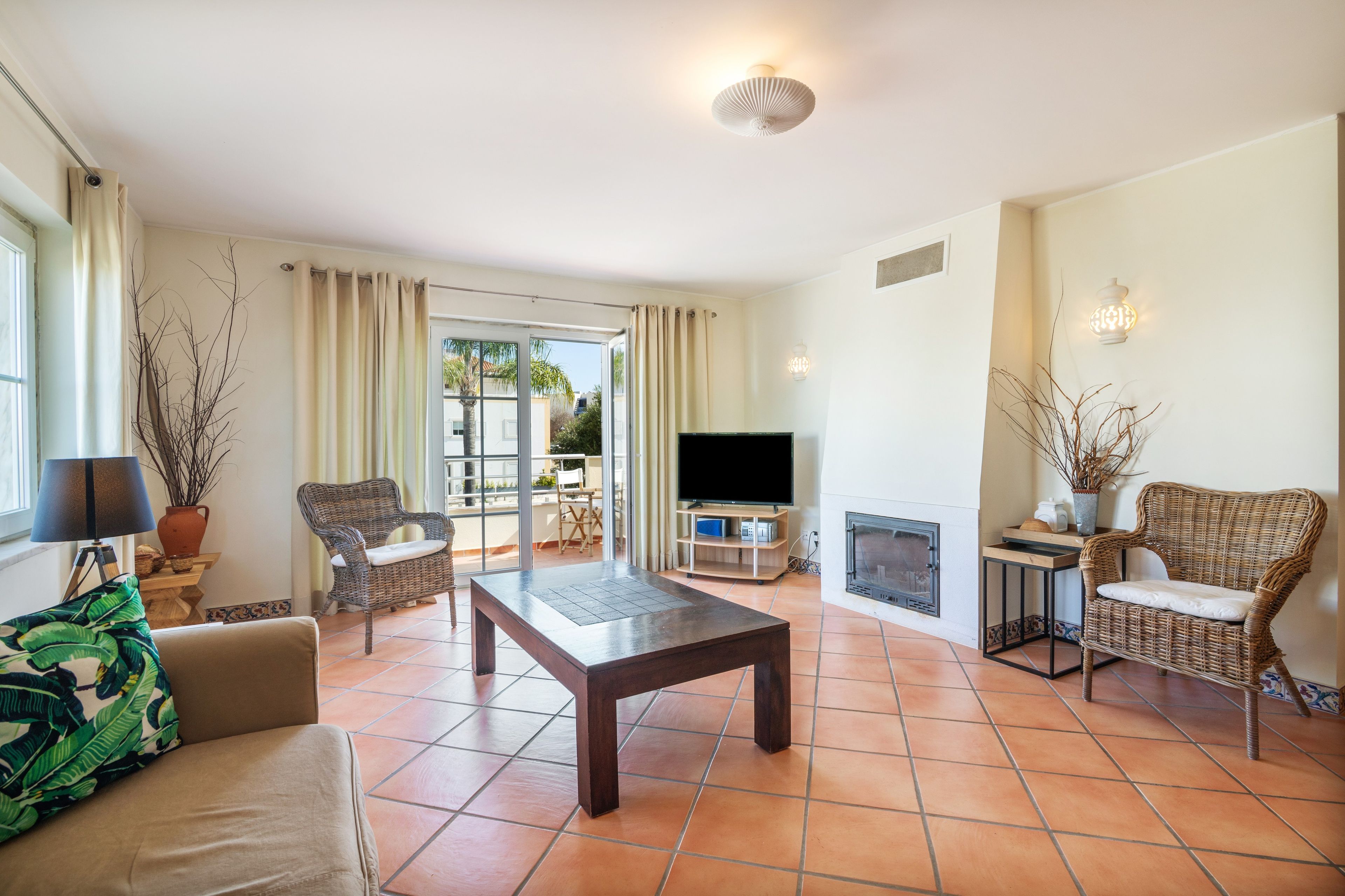 Una sala de estar con televisor, chimenea y balcón con cortinas.