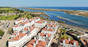 Et kystnært boligområde med hvide huse og røde tage, en strand og frit udsyn til havet.