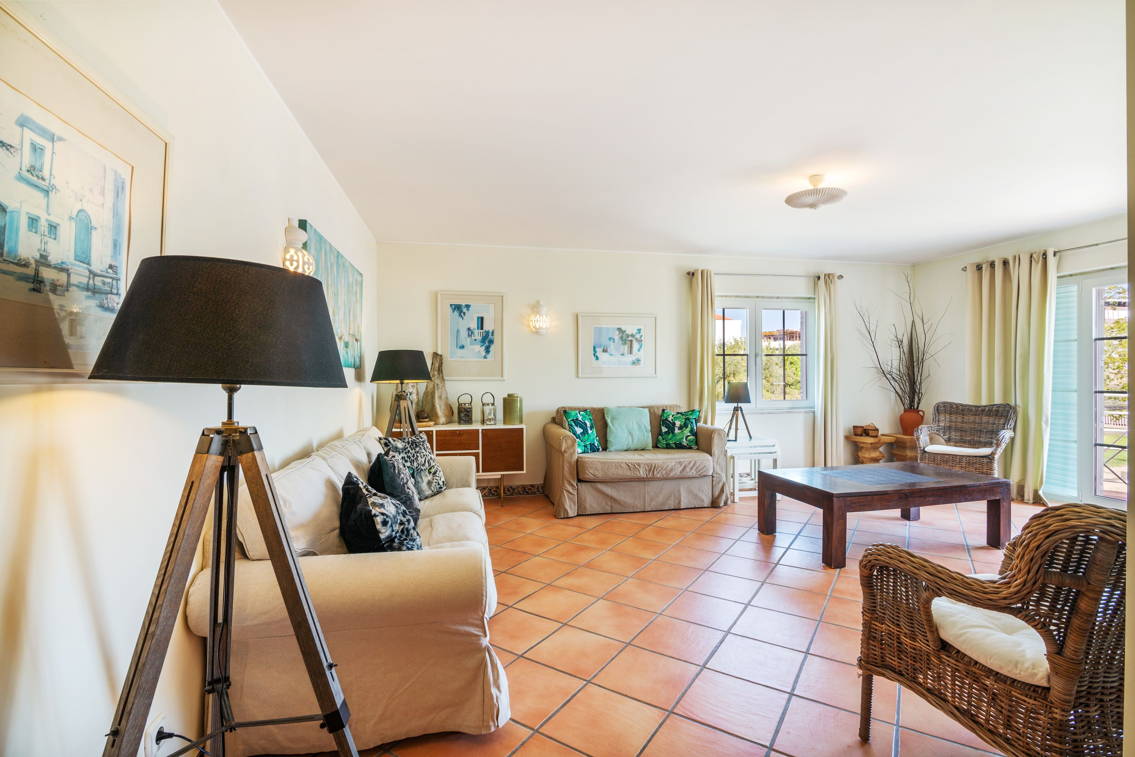 Ein Wohnzimmer mit einer Couch, einem Couchtisch, einer Lampe und einem Korbstuhl.