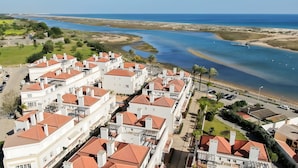 Una zona residencial a la costa amb edificis blancs i teulades vermelles, una platja i una vista clara del mar.